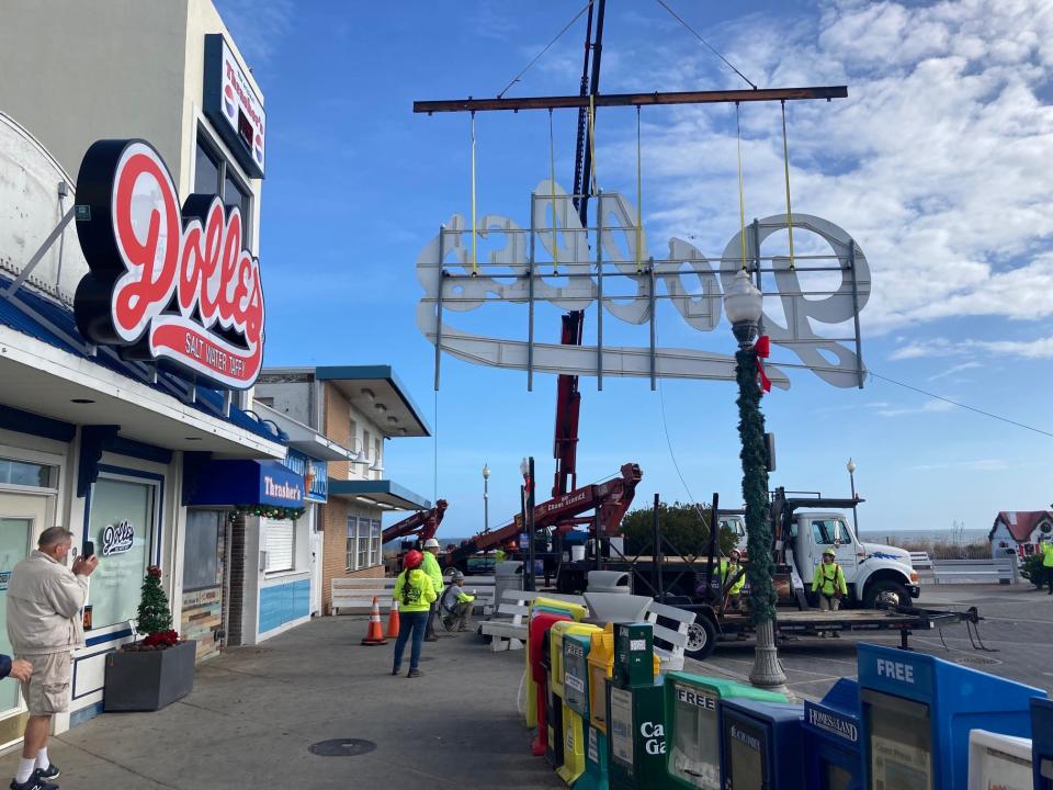 The historic Dolles sign is taken down from the Rehoboth Beach boardwalk. Owner Tom Ibach (far left) looks on.
