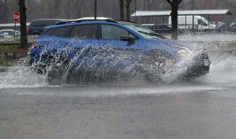 A car travels along a flooded section of Warehouse Lane in Elmsford during heavy rains March 23, 2024.