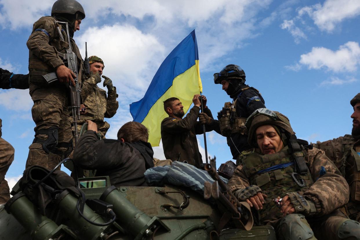 Ukrainian soldiers adjust a national flag atop a personnel armored carrier on a road near Lyman, Donetsk region on October 4, 2022, amid the Russian invasion of Ukraine.