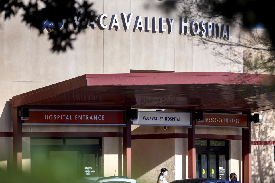 A person leaves NorthBay VacaValley Hospital, where a woman diagnosed with coronavirus previously sought treatment, on Thursday, Feb. 27, 2020, in Vacaville, Calif. Public health officials are retracing the steps of the woman, believed to be the first person in the U.S. to contract the highly contagious coronavirus without traveling abroad or coming in close contact with an international traveller. (AP Photo/Noah Berger)