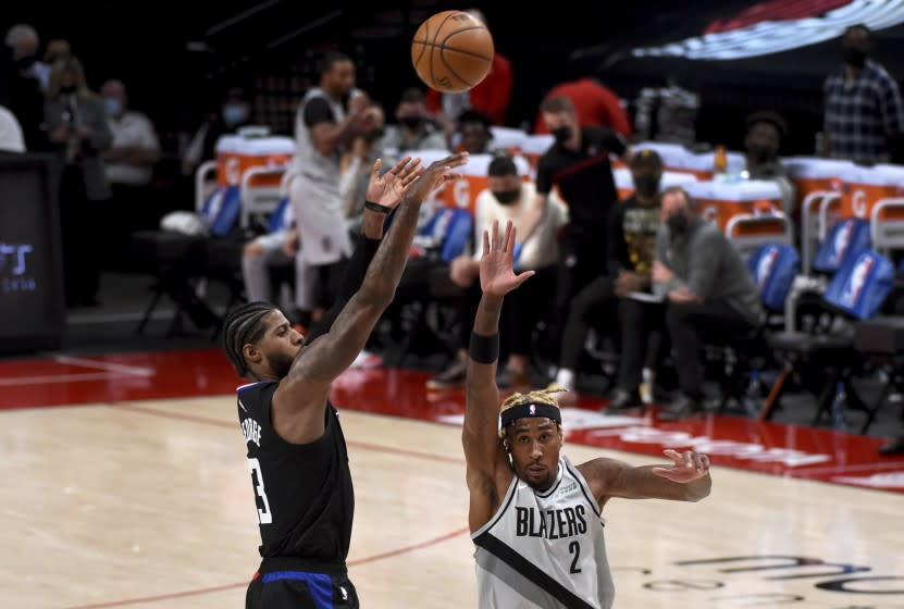 Los Angeles Clippers guard Paul George, left, hits a shot over Portland Trail Blazers forward Rondae Hollis-Jefferson, right, during the first half of an NBA basketball game in Portland, Ore., Tuesday, April 20, 2021. (AP Photo/Steve Dykes)