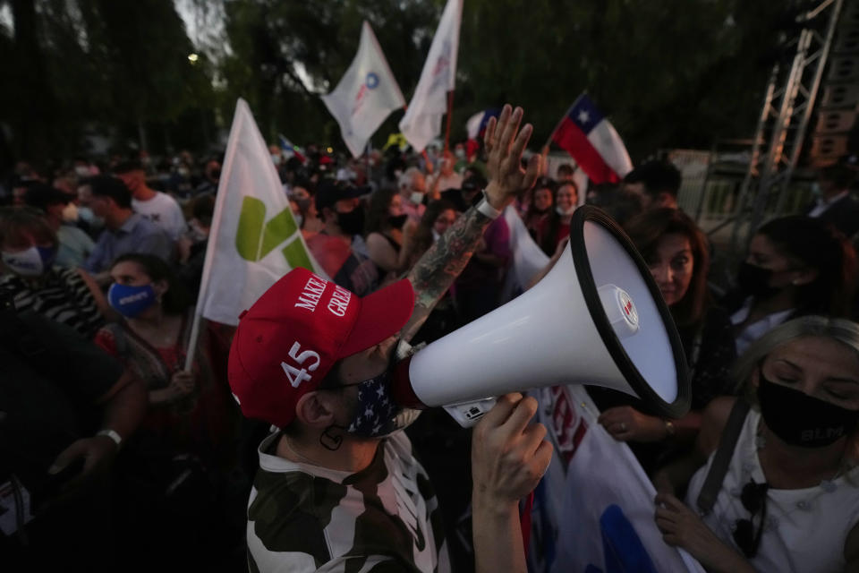 A supporter of Republican Party presidential candidate Jose Antonio Kast, wearing a MAGA hat, gathers with others outside Kast's election day headquarters after the announcement of partial results in Santiago, Chile, Sunday, Nov. 21, 2021. (AP Photo/Esteban Felix)