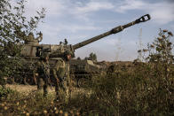 Two Israeli soldiers walk around an artillery unit, at the Israeli Gaza border, Sunday, May 16, 2021. (AP Photo/Heidi Levine)