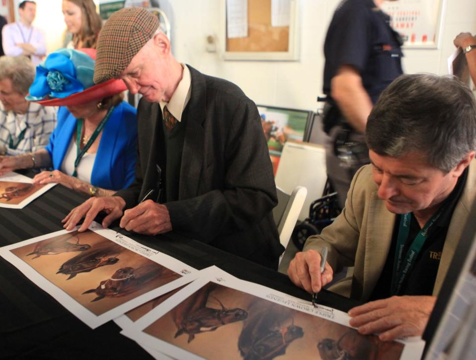 Jean Cruguet, right, jockey of Seattle Slew, and trainer Billy Turner, left, sign autographs at Belmont Park on June 6, 2015.