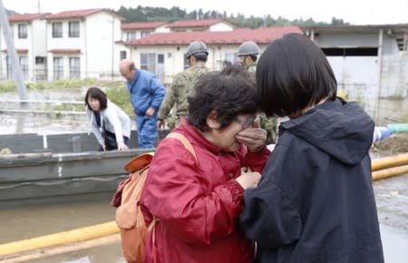 A woman cries in relief after being rescued from an area flooded by Typhoon Hagibis in Marumori, Miyagi prefecture