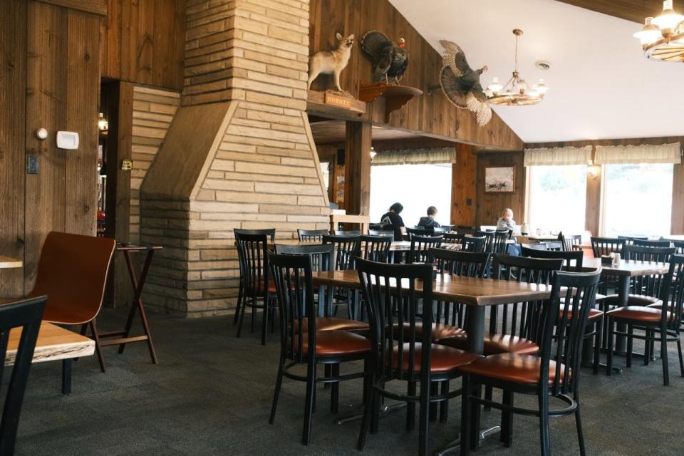 Carpeted dining room with large fireplace-like structure, tables and chairs