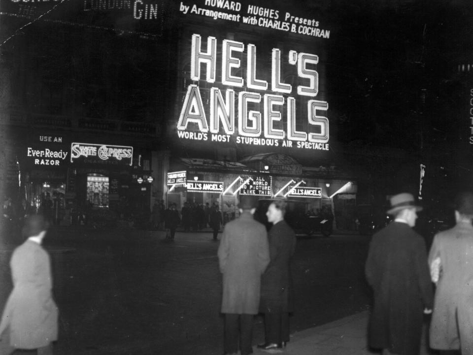 An exterior view of a West End cinema and its neon sign showing the Howard Hughes production "Hell's Angels."