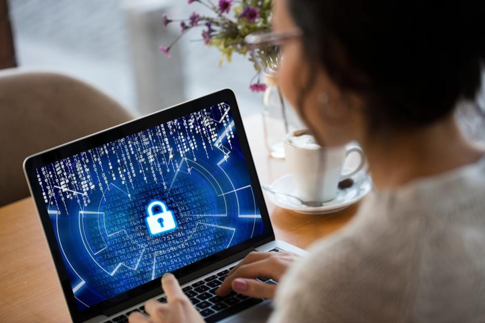 Person at desk utilizing computing device with abstract security representation.