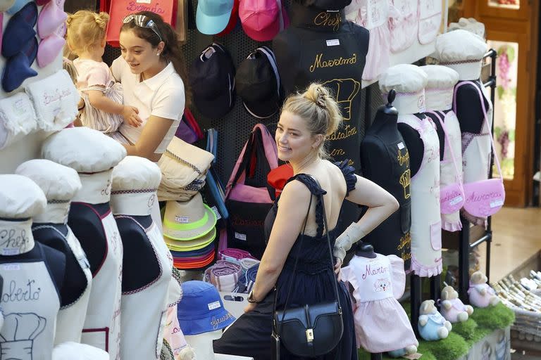 Amber Heard disfruta de los encantos del sur de Italia junto a su hija, con quien recorrió varios puestos de venta luciendo un vestido negro con un bolso haciendo juego