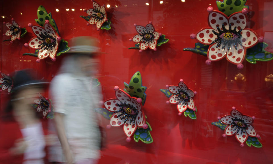 In this July 30, 2012 photo, a couple walks by a Louis Vuitton store decorated by Japanese artist Yayoi Kusama's window display at Tokyo's Ginza shopping district. Kusama's signature splash of dots has now arrived in the realm of fashion in a new collection from French luxury brand Louis Vuitton - bags, sunglasses, shoes and coats. The latest Kusama collection is showcased at its boutiques around the world, including New York, Paris, Tokyo and Singapore, sometimes with replica dolls of Kusama. (AP Photo/Shizuo Kambayashi)