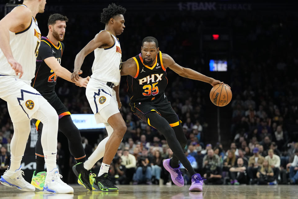 Phoenix Suns forward Kevin Durant (35) drives as Denver Nuggets forward Peyton Watson defends during the first half of an NBA basketball game, Friday, Dec. 1, 2023, in Phoenix. (AP Photo/Matt York)