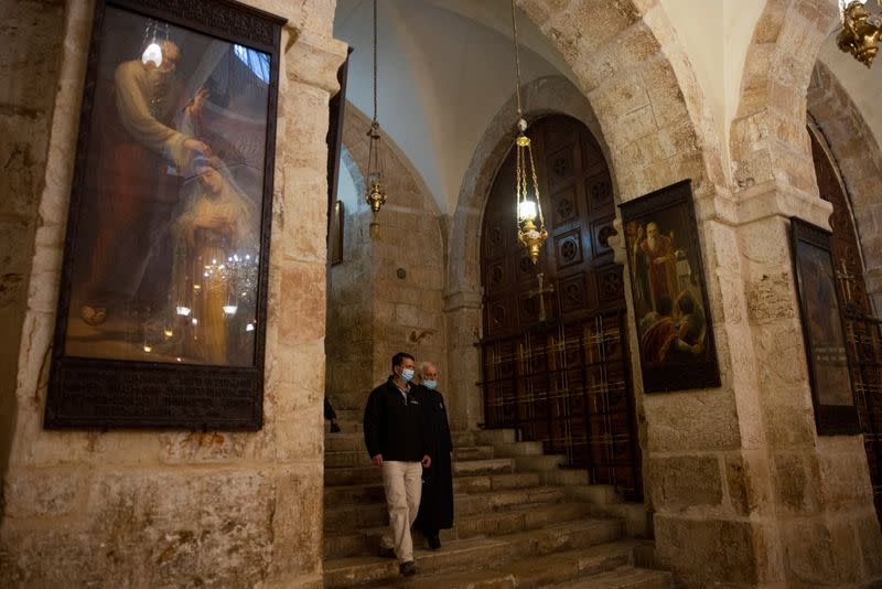 Re'em, Jerusalem regional archaeologist for Israel Antiquities Authority and Father Aghoyan, Armenian superior at Church of the Holy Sepulchre, walk in the Saint Helena chapel inside the church during an interview with Reuters, in Jerusalem's Old City