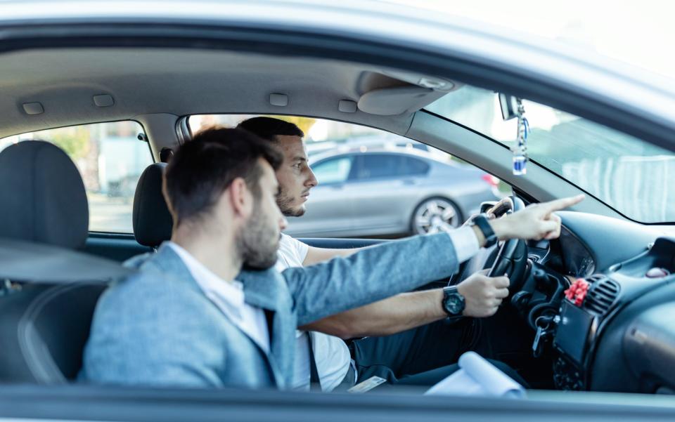 A driving instructor gives his student a lesson