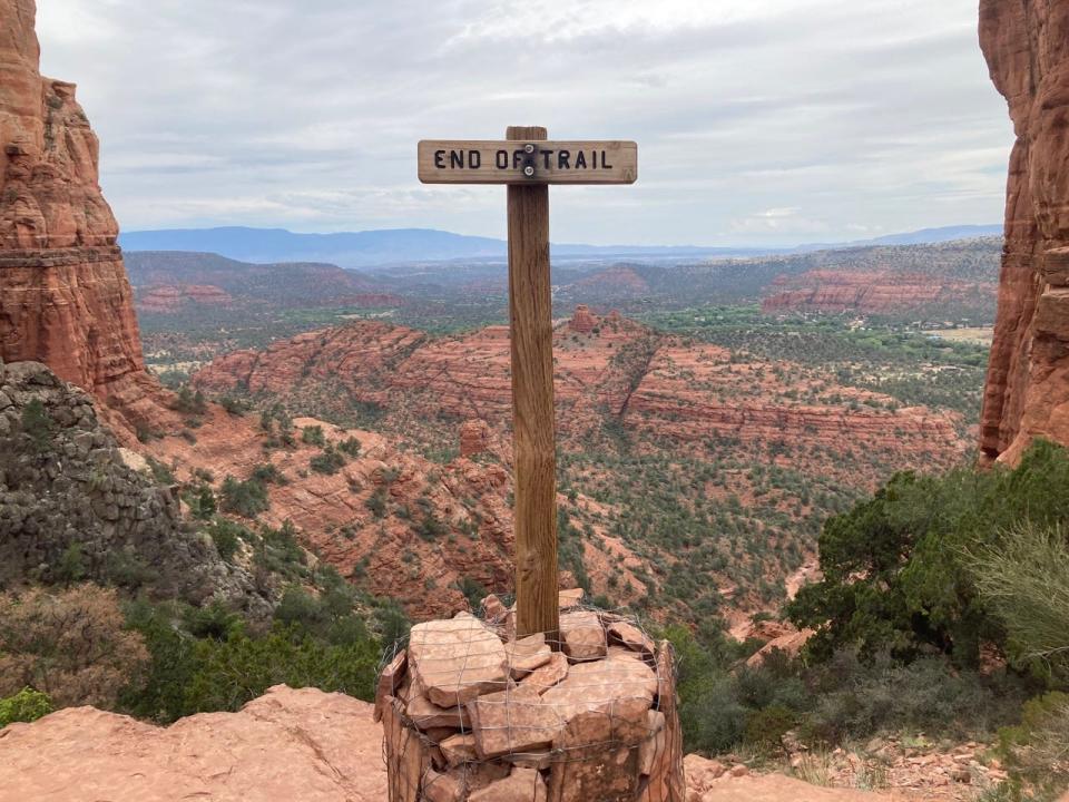 Wood sign in Arizona in front of canyon of trees and rock