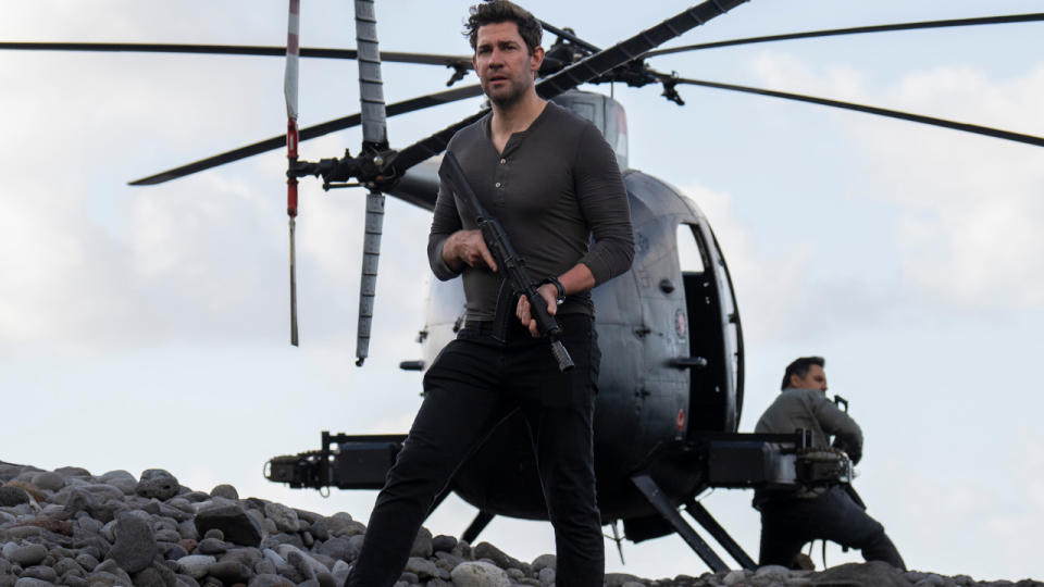 John Krasinski stands armed in front of a helicopter in Tom Clancy's Jack Ryan.