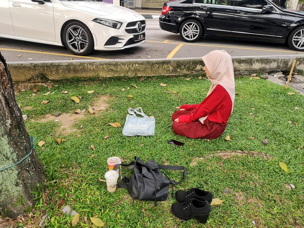 Aliyah Ibrahim Ali Choon completing her prayers while the Grab driver waited. — Twitter/ @AinulNunanaa