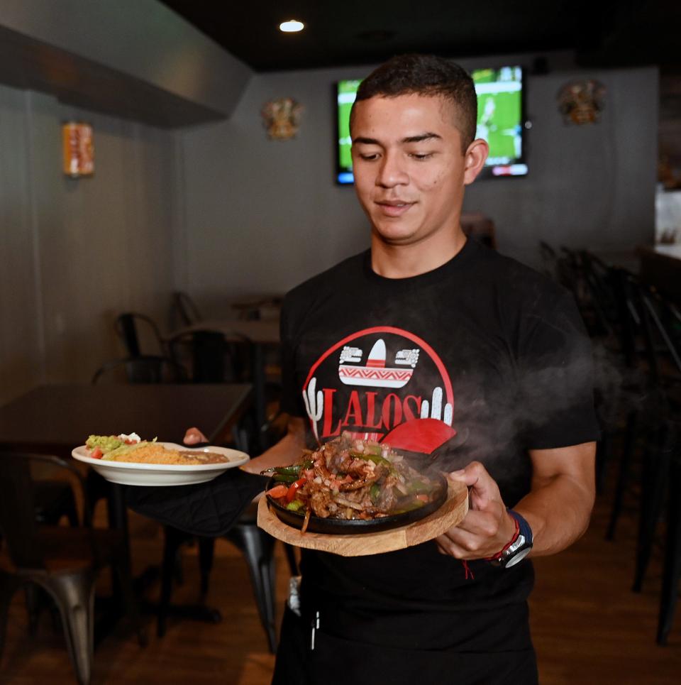 Manuel Moreno carries plates of fajitas and chimichanga at Lalo's Mexican Restaurant in Hudson, Aug. 26, 2021.