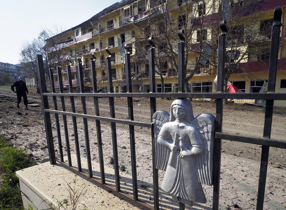 A man walks past an apartment building damaged by shelling by Azerbaijan's forces during a military conflict in Shushi, outside Stepanakert, the separatist region of Nagorno-Karabakh, Thursday, Oct. 29, 2020. Fighting over the separatist territory of Nagorno-Karabakh continued on Thursday, as the latest cease-fire agreement brokered by the U.S. failed to halt the flare-up of a decades-old conflict between Armenia and Azerbaijan. (AP Photo)