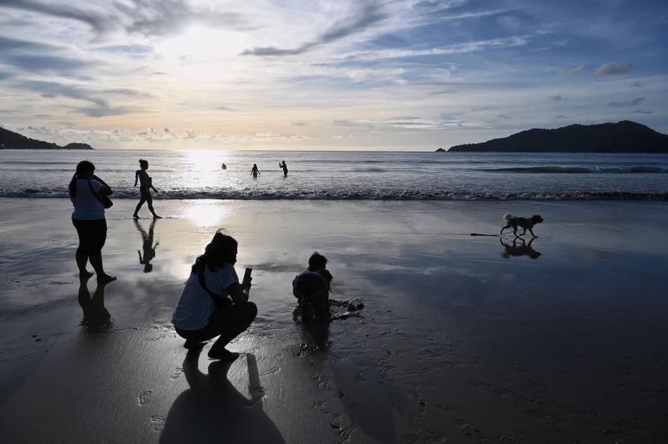 People walk along Patong Beach in Phuket, Thailand.