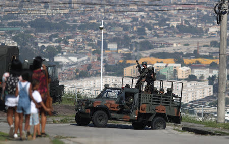 Residents walk past by Brazilian Army soldiers who patrol during an operation against drug dealers in the Alemao complex slum in Rio de Janeiro, Brazil August 20, 2018. REUTERS/Ricardo Moraes