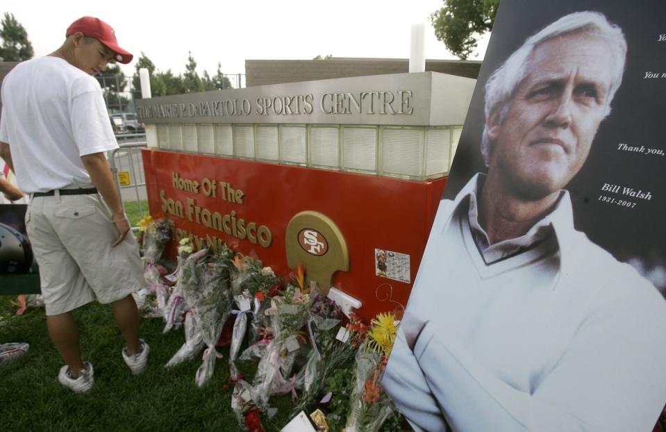 San Francisco 49ers intern Andrew Su, left, looks over a memorial for former head coach Bill Walsh outside of the 49ers’ practice facility Thursday, Aug. 2, 2007, in Santa Clara, Calif. | Jeff Chiu, Associated Press