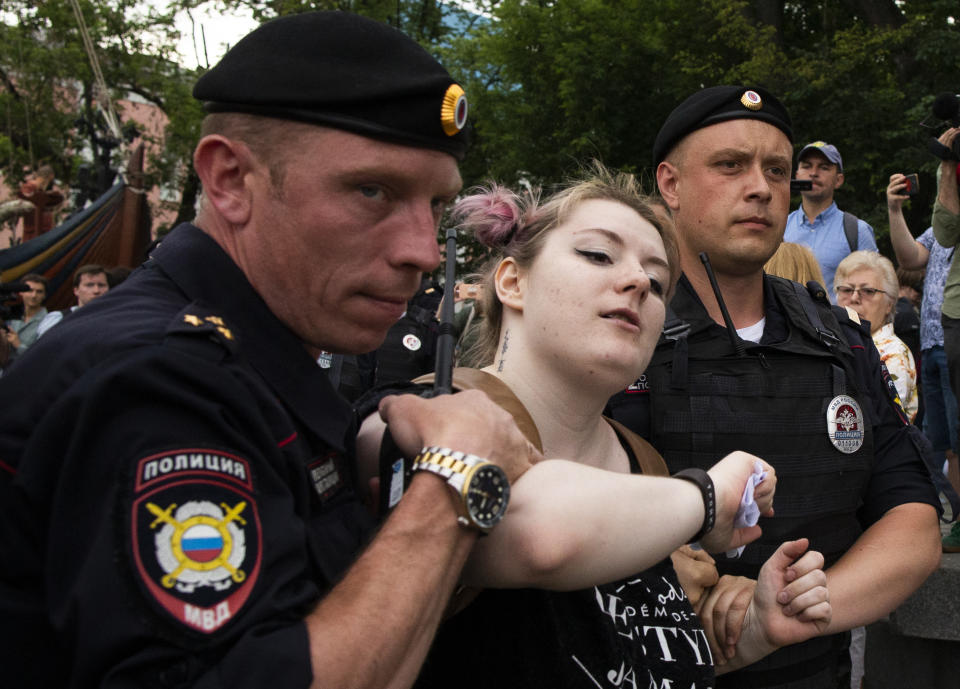 Police officers detain a woman during a march in Moscow, Russia, Wednesday, June 12, 2019. Police and hundreds of demonstrators are facing off in central Moscow at an unauthorized march against police abuse in the wake of the high-profile detention of a Russian journalist. More than 20 demonstrators have been detained, according to monitoring group. (AP Photo/Alexander Zemlianichenko)