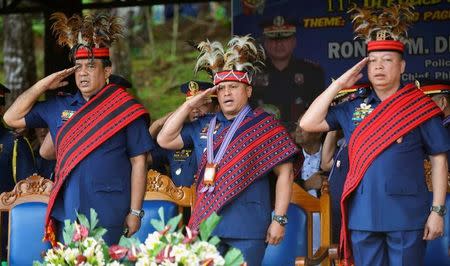 Philippine National Police Chief General Ronald "Bato" Dela Rosa (C) and other police officials salute as they wear local Igorot tribe headdress while singing the national anthem during a visit at police Camp Dangwa, Benguet province in northern Philippines September 2, 2016. REUTERS/Ezra Acayan