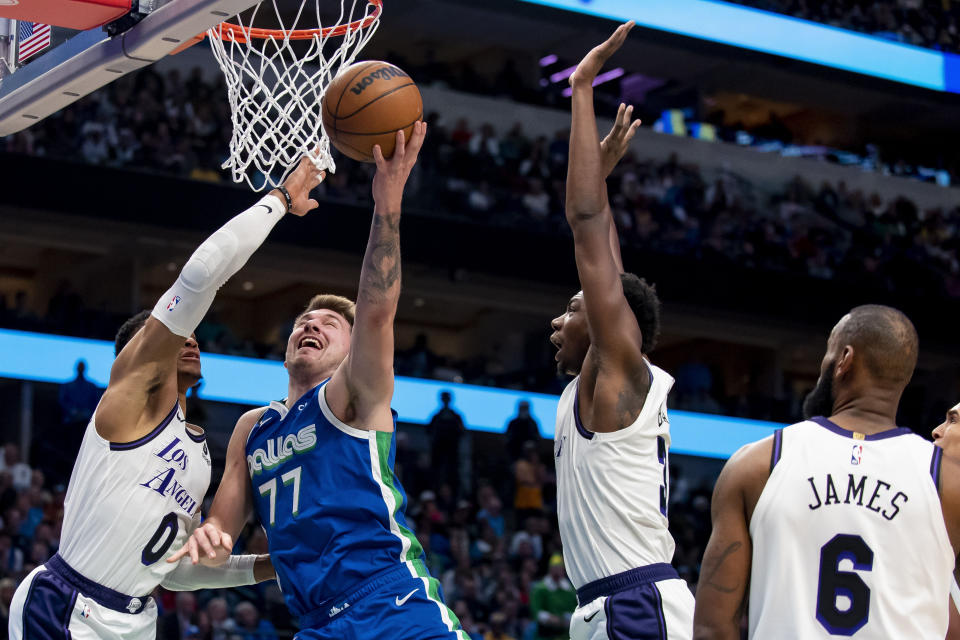 Dallas Mavericks guard Luka Doncic (77) goes up for a shot while Los Angeles Lakers guard Russell Westbrook (0) and Los Angeles Lakers center Thomas Bryant defend him in the second half of an NBA basketball game in Dallas, Sunday, Dec. 25, 2022. (AP Photo/Emil T. Lippe)