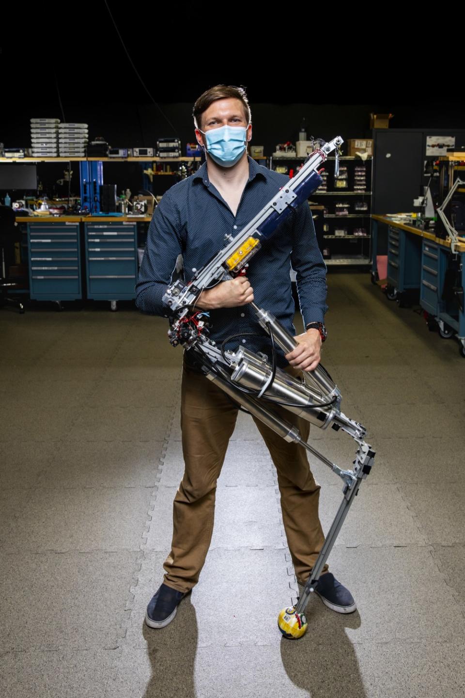 A man wearing a face mask holds a robotic figure