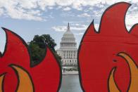 The U.S. Capitol is seen between cardboard cutouts of flames during a climate change protest by people including indigenous and youth activists, Friday, Oct. 15, 2021, by the U.S. Capitol in Washington. (AP Photo/Jacquelyn Martin)