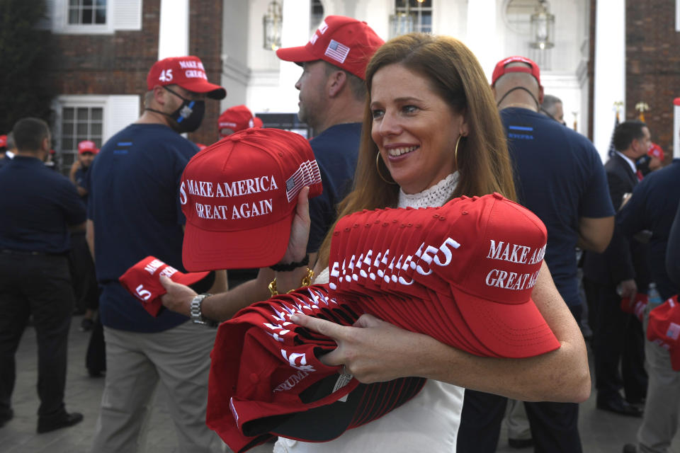 Hats are passed out before President Donald Trump speaks to the City of New York Police Benevolent Association at an event at the Trump National Golf Club in Bedminster, N.J., Friday, Aug. 14, 2020. (AP Photo/Susan Walsh)