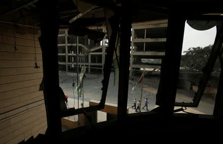 Palestinians are seen through windows of the Ministry of Religious Affairs that was damaged by Israeli air strikes in Gaza City July 15, 2018. REUTERS/Suhaib Salem