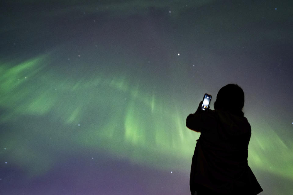 A person takes a photo of Aurora Borealis or the Northern Lights in Vancouver, B.C., Saturday, May. 11, 2024. (Ethan Cairns /The Canadian Press via AP)