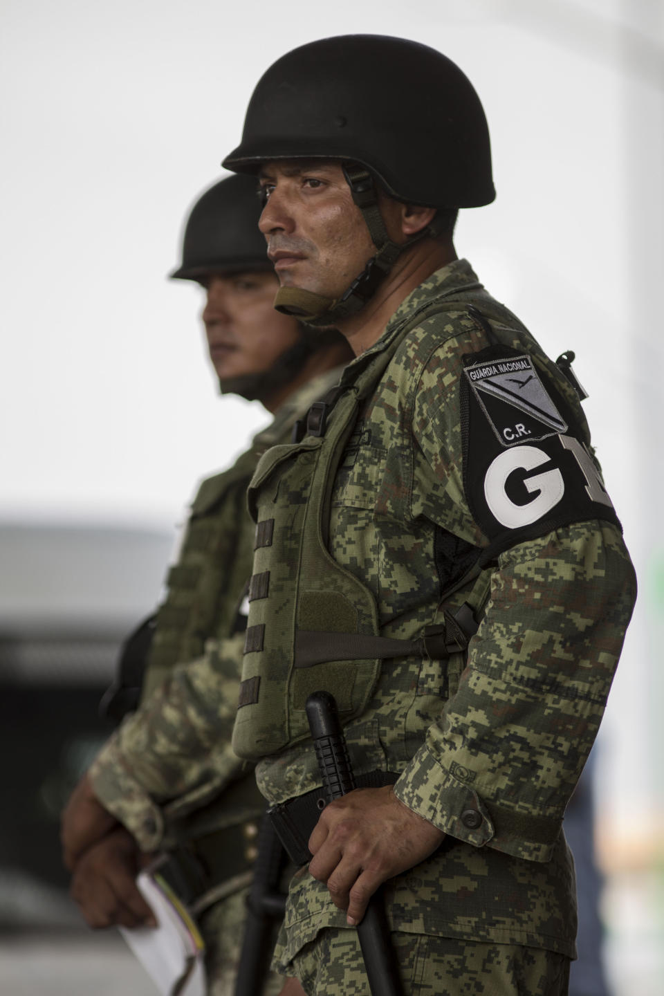 Military police wearing the insignia of the new National Guard provide perimeter security while a migration agent waits to check documents of bus passengers, at an immigration checkpoint in El Manguito, south of Tapachula, Mexico, Friday, June 21, 2019. Mexico's foreign minister says that the country has completed its deployment of some 6,000 National Guard members to help control the flow of Central American migrants headed toward the U.S. (AP Photo/Oliver de Ros)