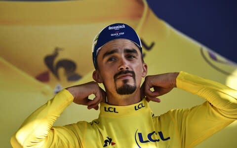 Julian Alaphilippe adjusts his overall leader's yellow jersey on the podium - Credit: afp