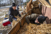 Rick Haaland holds a door for Preston Lassman as Elaine Fleming brings straw to be used in a large shelter on the front of Elaine's house in Cass Lake, Minn., on Sunday, Nov. 21, 2021. Elaine takes in stray and abandoned cats that often show up at her house to seek shelter. Haaland and Fleming have been leading efforts among their fellow Ojibwe community members to care for animals, something centrally important to Native American spiritual beliefs and traditions. (AP Photo/Jack Rendulich)