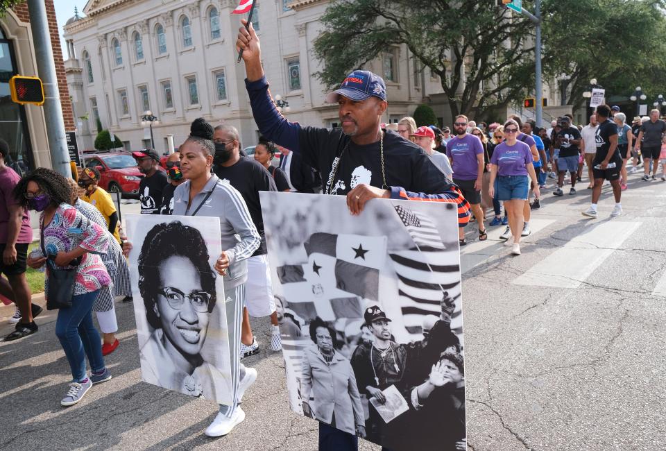 Trina and Dennis Lewis march with posters depicting the late civl rights icon Clara Luper during the 2022 reenactment of the Oklahoma City sit-ins. The march to Kaiser’s Grateful Bean Café had begun at Frontline Church.
