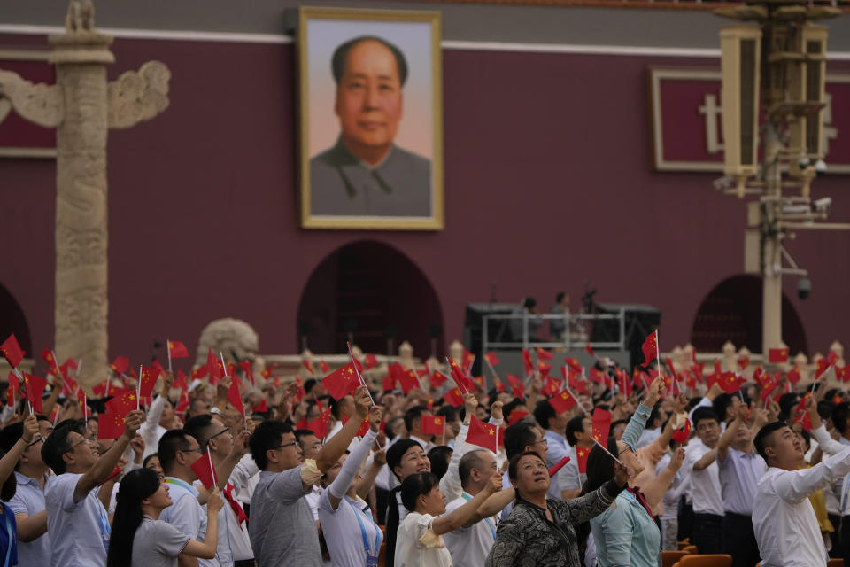 People wave Chinese flags beneath a large portrait of the late leader Mao Zedong during a ceremony to mark the 100th anniversary of the founding of the ruling Chinese Communist Party at Tiananmen Gate in Beijing Thursday, July 1, 2021. (AP Photo/Ng Han Guan)