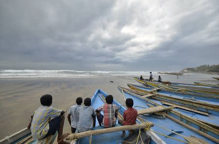 Children sit on fishing boats by the shore before being evacuated, at Visakhapatnam district in Andhra Pradesh October 11, 2014. REUTERS/R Narendra