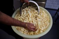 Owner of Hooked Fish and Chips shop, Bally Singh, scoops potato chips ready to be cooked at his take-away in West Drayton
