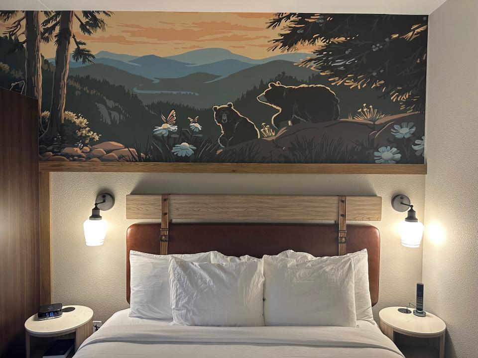 Artwork of bears in Smoky Mountains above king-size bed with leather and wood headboard at HeartSong Dollywood resort