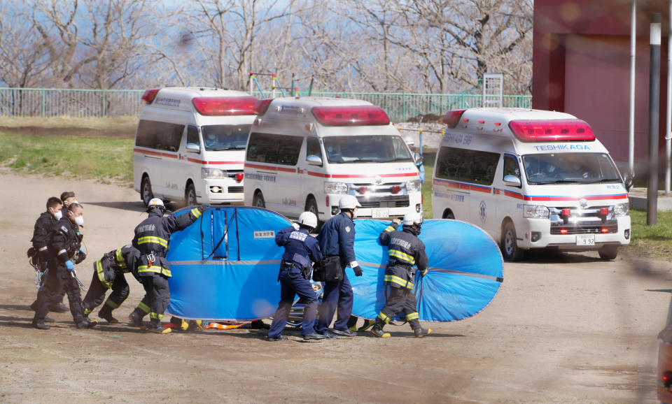 ADDS STORY UPDATE- Firefighters transfer a person retrieved from the tour boat accident, in Shari, in the northern island of Hokkaido Sunday, April 24, 2022. The tour boat with 26 aboard sank in rough waters Saturday. Ten people are confirmed to have died and the search continues for the other 16. (Koki Sengoku/Kyodo News via AP)