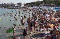 People enjoy the beach in the Black Sea in Odessa, Ukraine, Saturday, July 4, 2020. Tens of thousands of vacation-goers in Russia and Ukraine have descended on Black Sea beaches, paying little attention to safety measures despite levels of contagion still remaining high in both countries. (AP Photo/Sergei Poliakov)