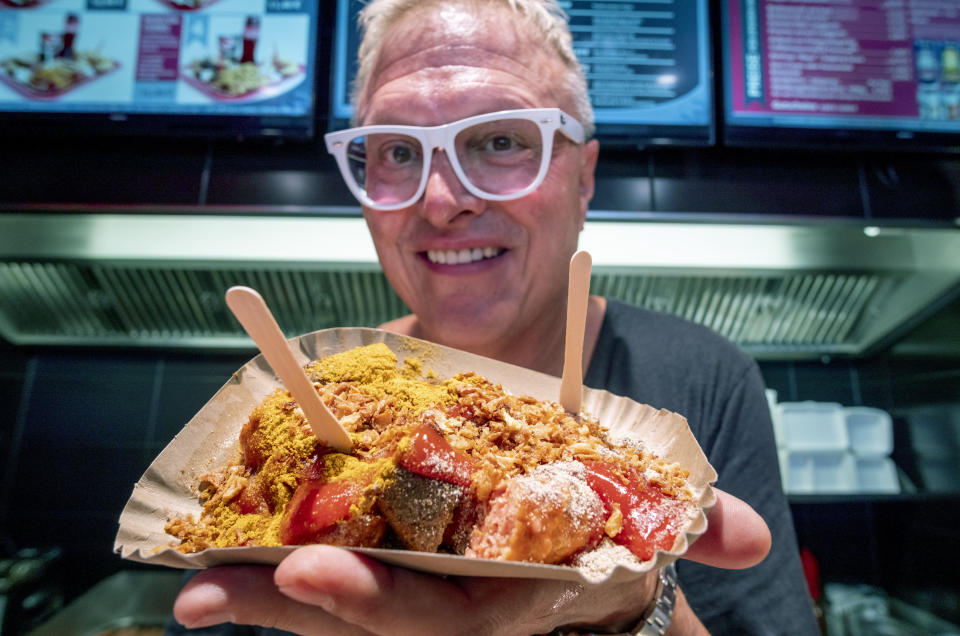 Lars Obendorfer, owner of "Best Worscht in Town" sausage holds up vegan curry wursts in one of his branches in Frankfurt, Germany, Tuesday, Sept. 5, 2023. “There was downright hostility between the meat eaters and the vegans,” he says. “And I just couldn’t understand it, and I said, ‘knock off the arguing.’” (AP Photo/Michael Probst)