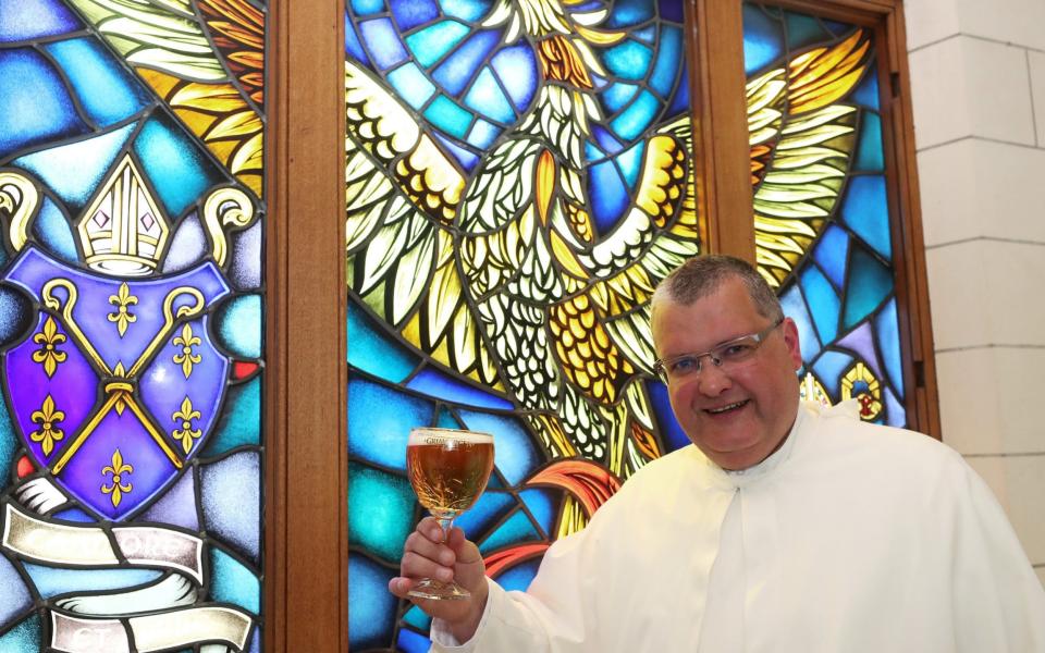 Norbertine Father Karel poses with a Grimbergen beer, symbolised by a phoenix, in the courtyard of the Belgian Abbey of Grimbergen - REUTERS