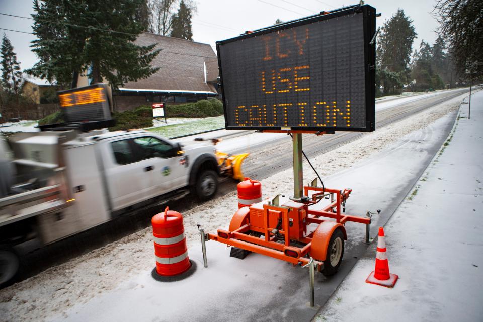 A city snowplow passes a sign warning of icy conditions on East 30th Avenue during a winter storm Saturday, Jan. 13, 2024, in Eugene, Ore.