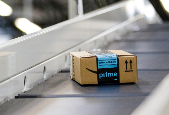 An Amazon package traveling on a conveyor belt in a fulfillment center.