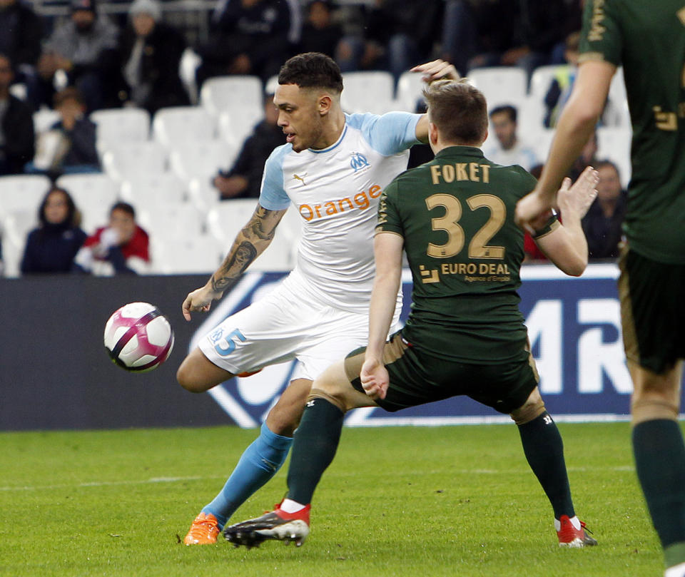 Marseille's Lucas Ocampos, left, challenges for the ball with Reims' Romain Metanire, during the League One soccer match between Marseille and Reims at the Velodrome stadium, in Marseille, southern France, Sunday, Dec. 2, 2018. (AP Photo/Claude Paris)