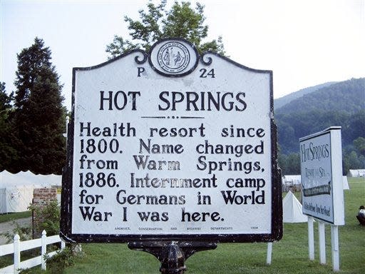 This June 4, 2011, photo shows a sign marking the tiny Blue Ridge Mountain town of Hot Springs, N.C. Tents from a popular Civil War re-enactment are visible in the background. Hot Springs sits at the confluence of the French Broad River and Spring Creek, and is named after natural mineral hot springs bubbling up from those waters. (AP Photo/Lindsey Tanner)