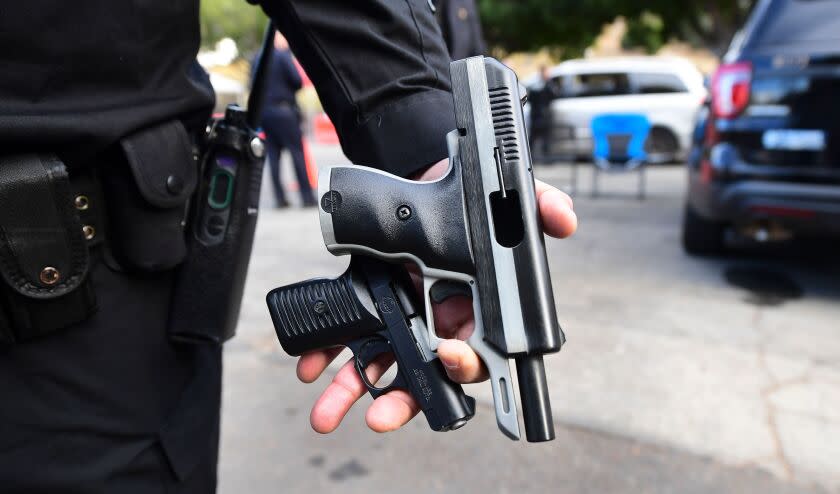 A Los Angeles Police Department officer displays recovered guns from residents turning in firearms at a "Gun Buy Back" event taking place in three locations across Los Angeles, California on December 5, 2020. - The "Gun Buy Back" program is used by the LAPD to help reduce gun violence, improve security in communities and those participating can anonymously turn in firearms in exhange for giftcards valued at $100 for handguns, shotguns and rifles and $200 for assault weapons, as classified by the state of California. (Photo by Frederic J. BROWN / AFP) (Photo by FREDERIC J. BROWN/AFP via Getty Images)